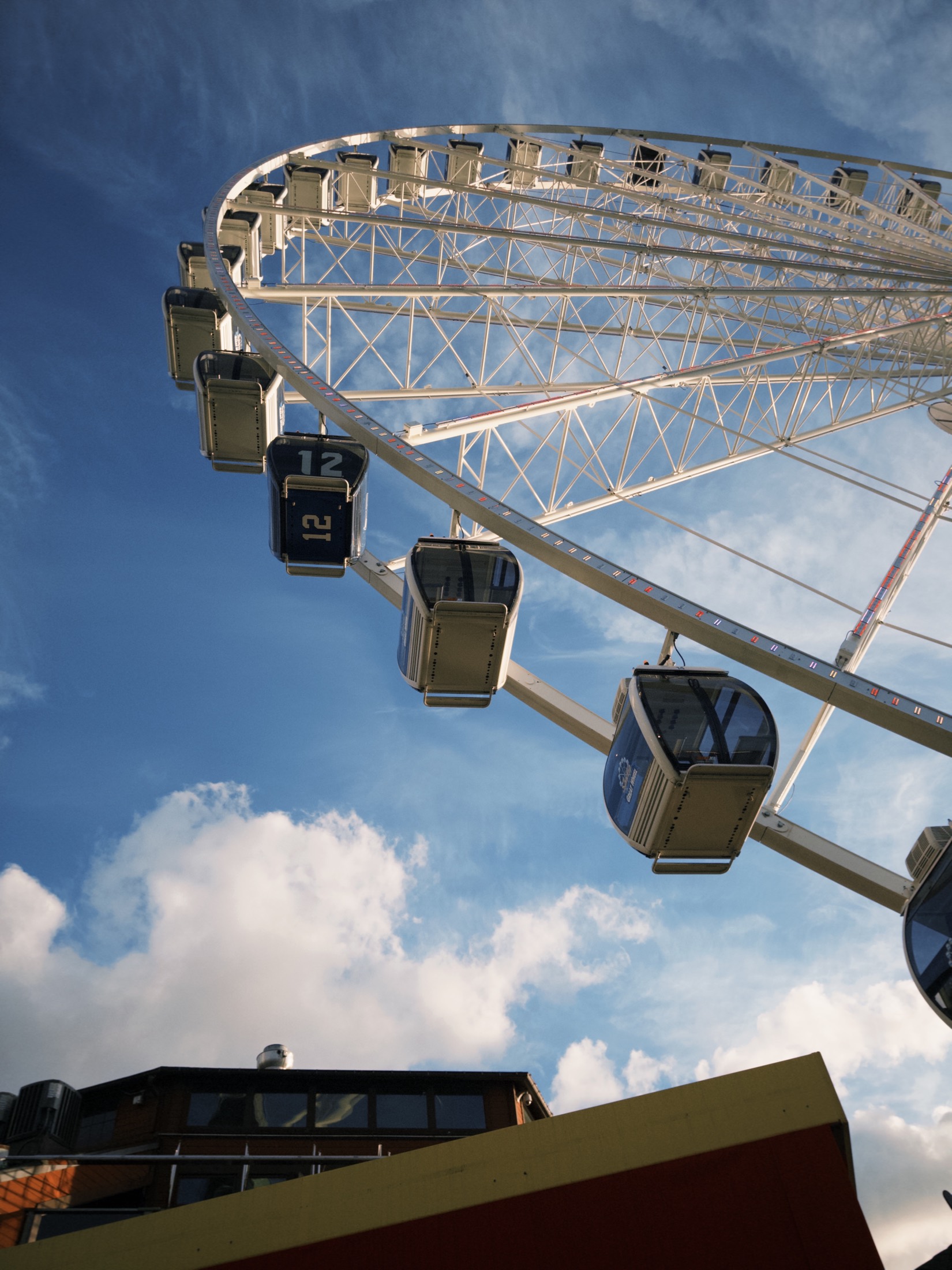 Seattle Great Wheel cabins seen from below against blue sky and clouds.